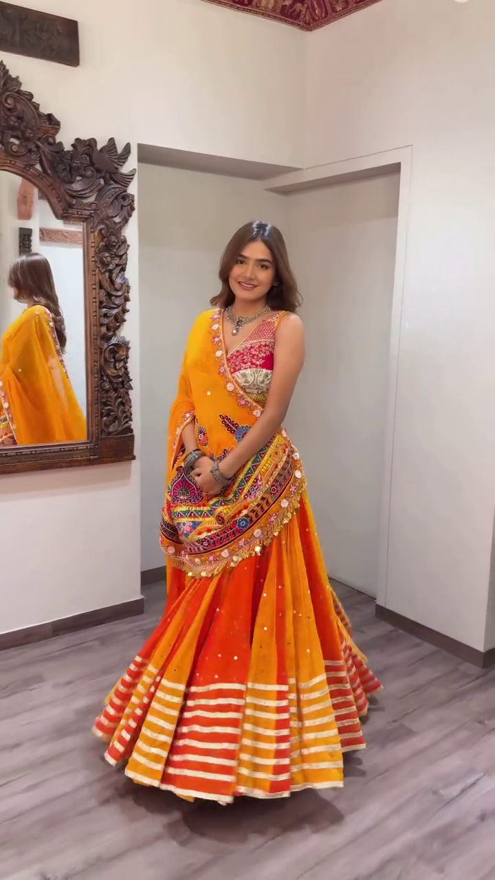 Orange and Yellow Traditional Navratri Lehenga Choli Set with Mirror Work, Thread Embroidery, and Vibrant Striped Flared Skirt Paired with Heavily Embellished Dupatta – Perfect for Garba Nights