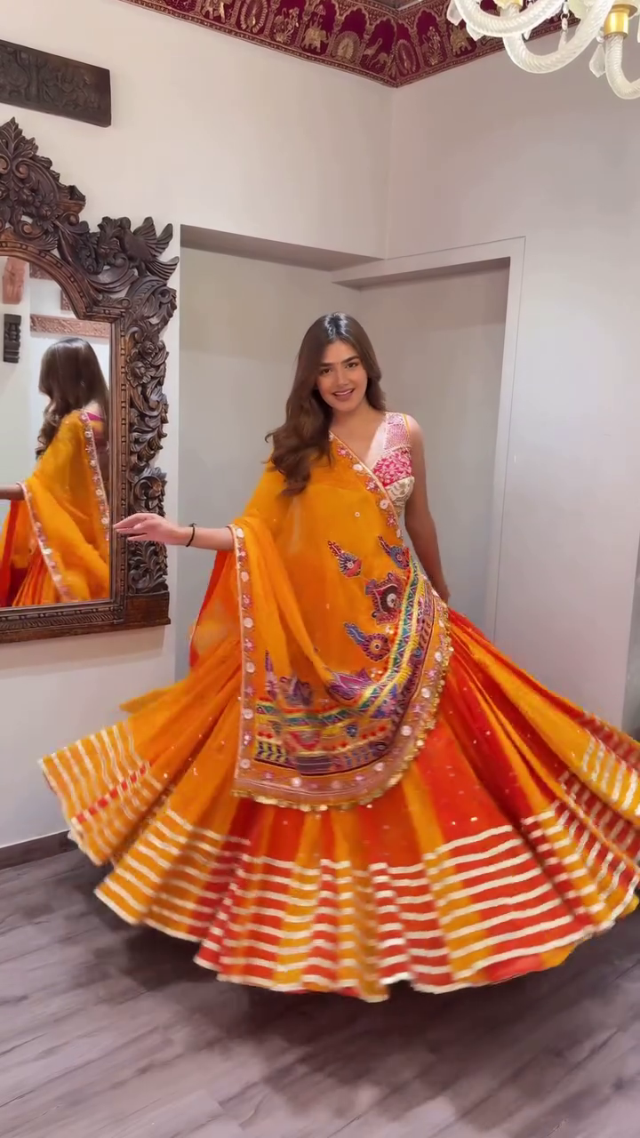 Orange and Yellow Traditional Navratri Lehenga Choli Set with Mirror Work, Thread Embroidery, and Vibrant Striped Flared Skirt Paired with Heavily Embellished Dupatta – Perfect for Garba Nights