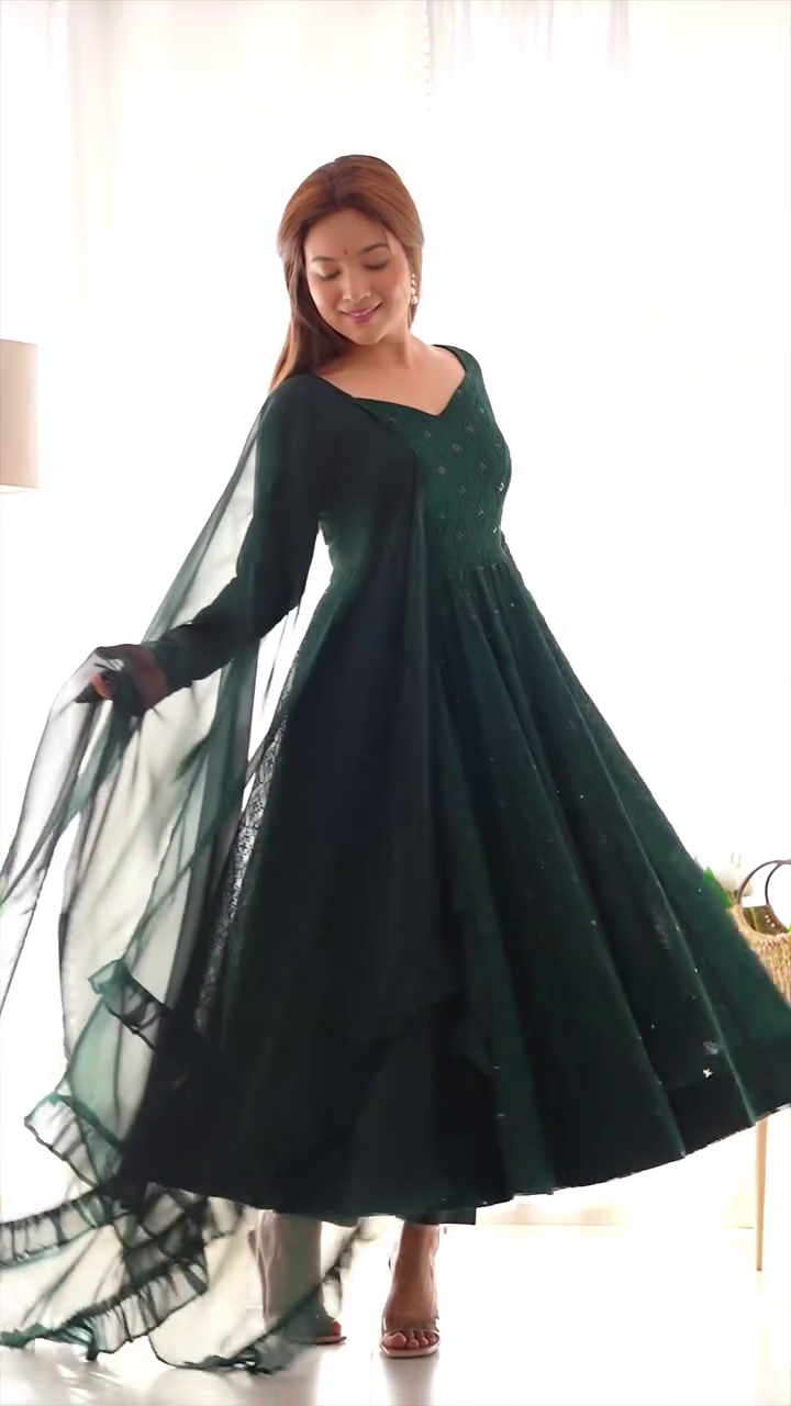A stunning emerald green gown with delicate embroidery, paired with a flowing sheer cape, creating a graceful, elegant look. Perfect for formal or festive events.