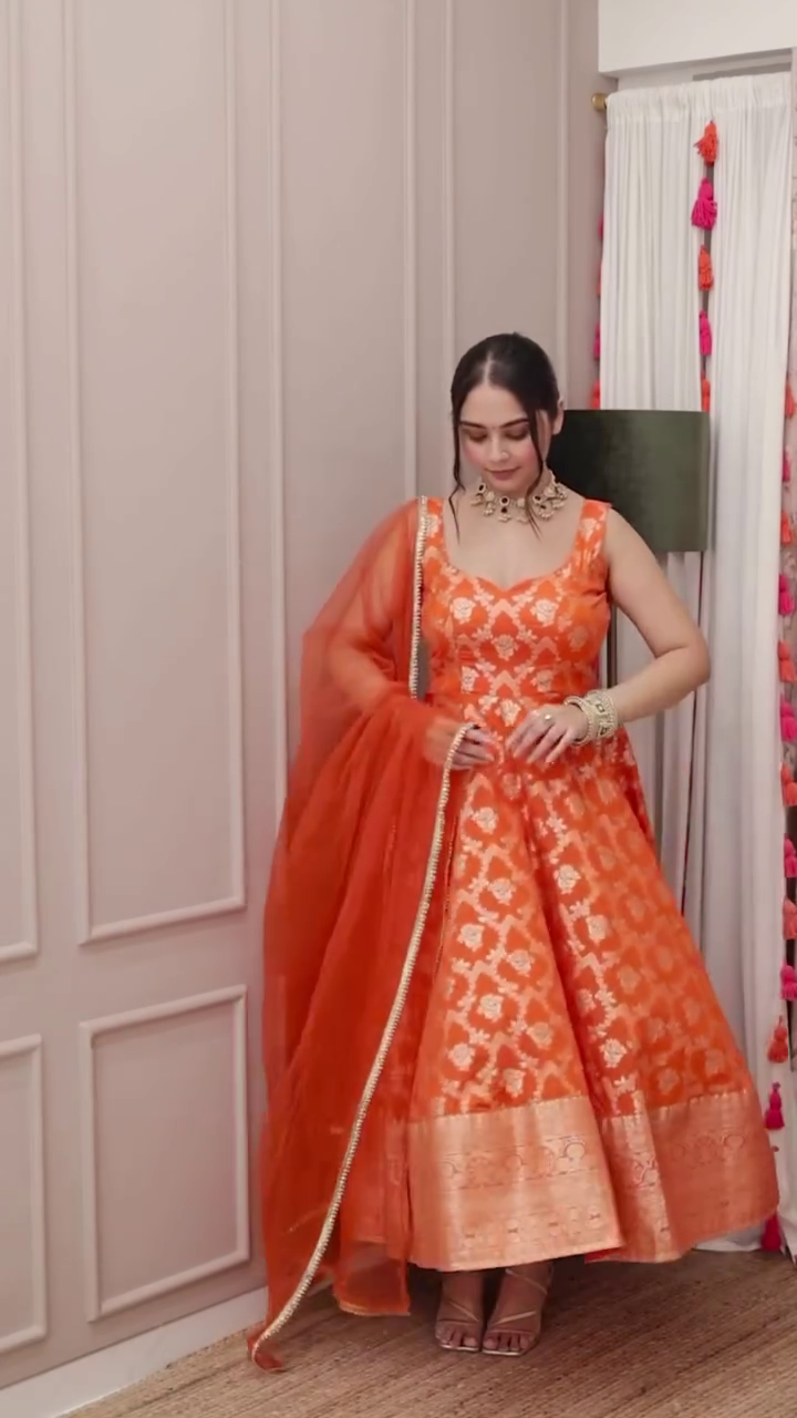 Radiant Orange Banarasi Silk Anarkali with Intricate Golden Zari Weaving and Matching Sheer Dupatta – Sleeveless Festive Ensemble Featuring Traditional Motifs and Rich Border Detailing, Perfect for Weddings, Navratri, and Grand Celebrations